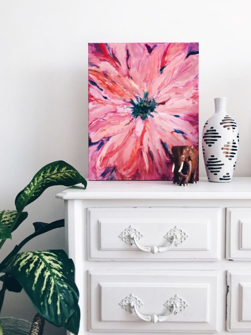 A white dresser with some vases and a painting on it