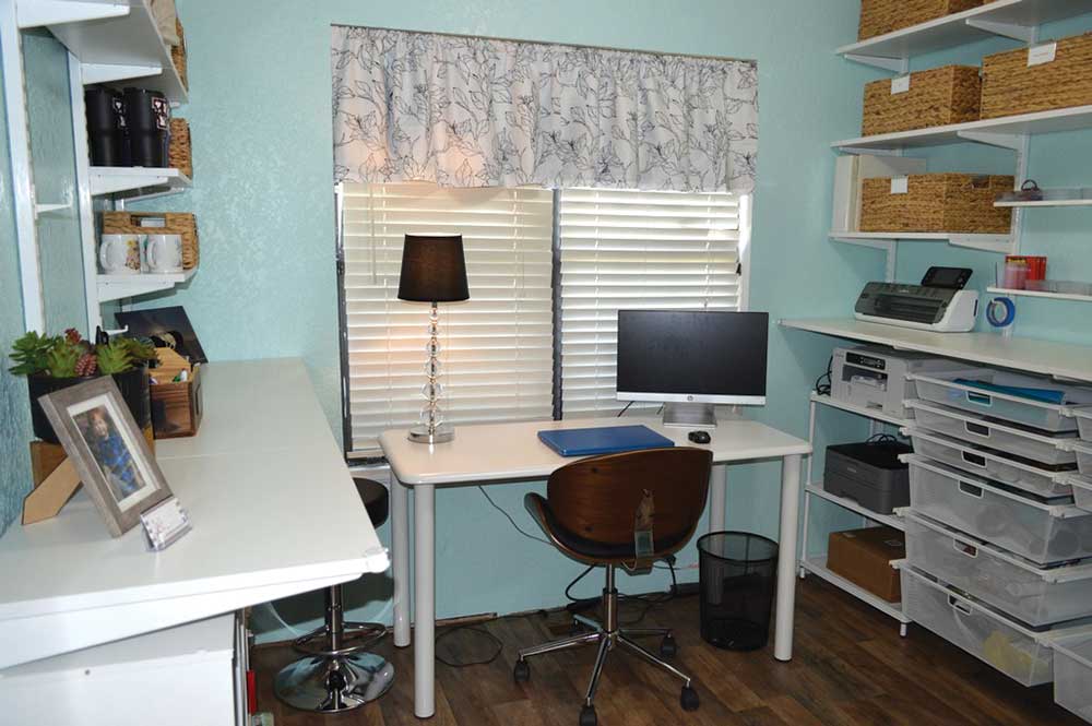 A desk with a computer and chair in front of a window.