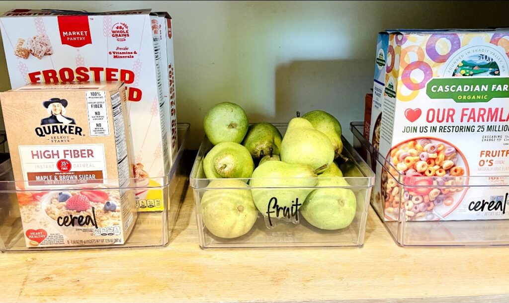 A shelf with apples and cereal boxes on it.