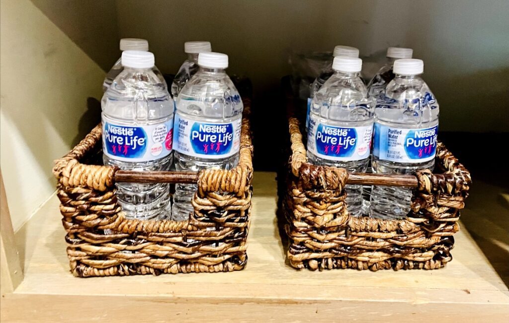 Two baskets with water bottles in them on a shelf.