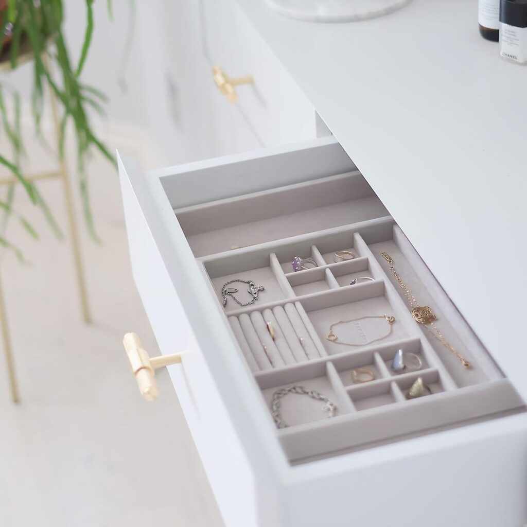 A white desk with some drawers and plants