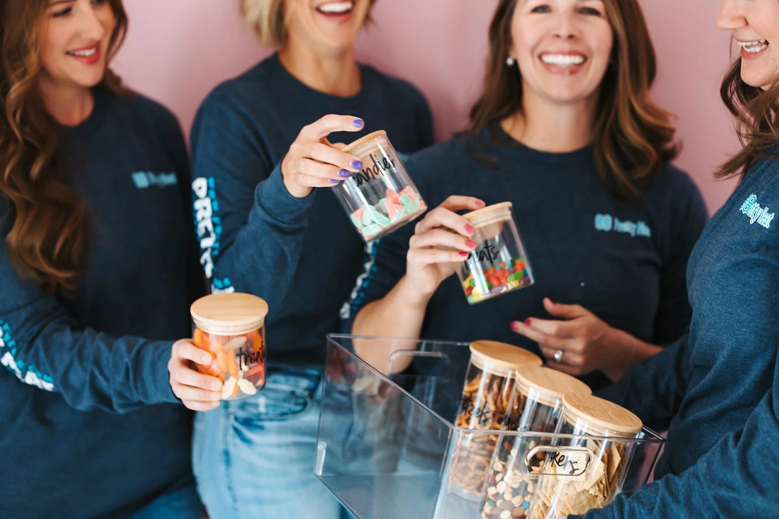 Three women holding bags of cookies and drinking coffee.