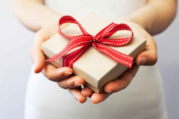pretty-neat-edmond-ok-experience-gift-guide-woman-holding-small-gift-box-with-red-bow-well-being-move-management-services