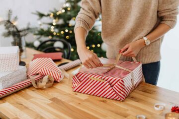 pretty-neat-oklahoma-city-ok-gift-wrap-organizing-solutions-woman-wrapping-gift-at-table-by-christmas-tree-decluttering-professional-home-organizing