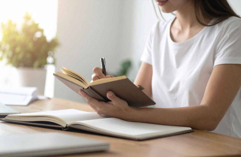 pretty-neat-oklahoma-city-ok-non-physical-ways-to-organize-woman-journaling-at-desk-by-window-decluttering-professional-home-organizing