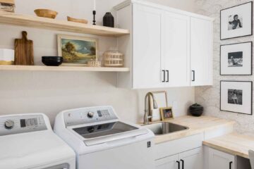 pretty-neat-edmond-ok-laundry-room-organization-tips-washer-and-dryer-wooden-shelves-sink-patterned-wallpaper-decluttering-home-organization